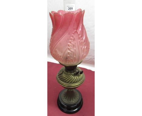 Early 20th Duplex brass paraffin lamp, with relief moulded and etched cranberry coloured shade, embossed brass body on circul
