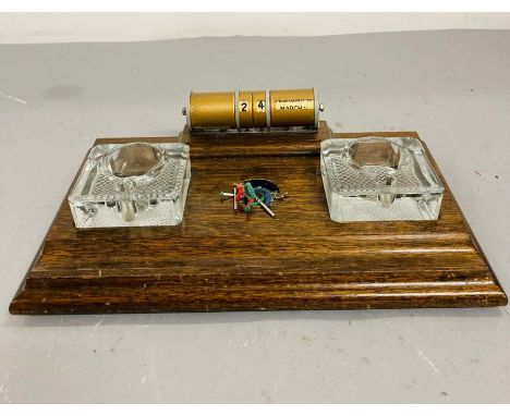 A wooden vintage perpetual desk calendar with two glass inkwell
