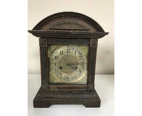 A late nineteenth century oak fourteen day strike mantle clock with brass face