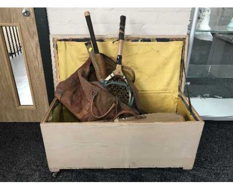 A painted pine blanket box containing two leather bags of vintage cricket equipment, tennis rackets, hockey stick etc 