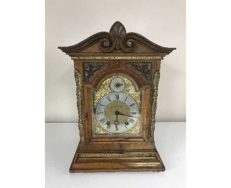 A carved mahogany cased bracket clock with brass dial and mounts 