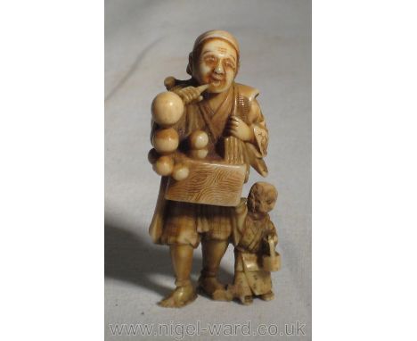 A finely carved and detailed Netsuke of a travelling musician and his son, Ivory, Meiji, 19th century, signed Kogyoku (faults