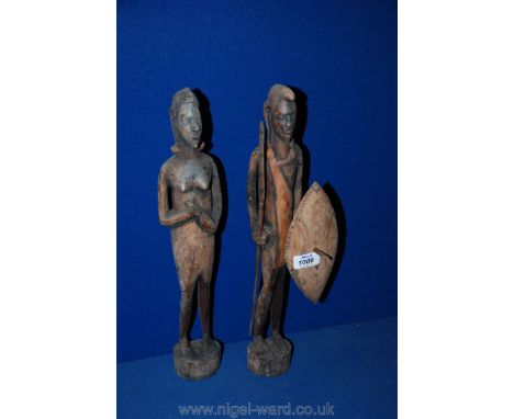 A pair of African carved wood figures depicting a Zulu style warrior with a spear and a shield and his female partner carryin