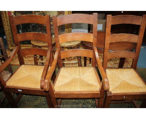 A set of six contemporary Oak ladder back Dining Chairs (including two carvers) having three bar backs, rush seats, standing 