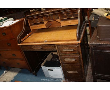 A Ministry Roll top Desk having tambour roller opening to reveal eleven pigeon holes and two short drawers, on single pedesta