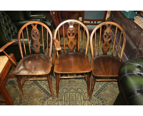 A set of three (including one carver) splat and stickback Ercol style Chairs having fleur de lys motif to the splats, solid s