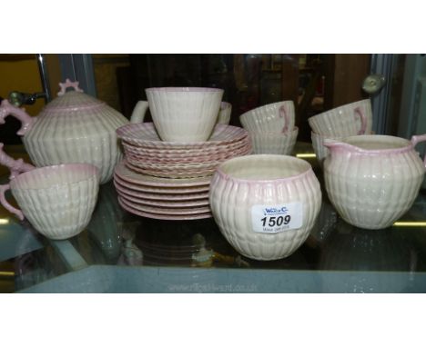 A Belleek Tea Service; blush pink and shell style including teapot, six plates, seven cups and saucer, (one cup damaged), sim