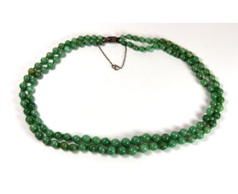 A 1920's two row graduated jade necklace mounted with its original white metal clasp, L. 42cm.