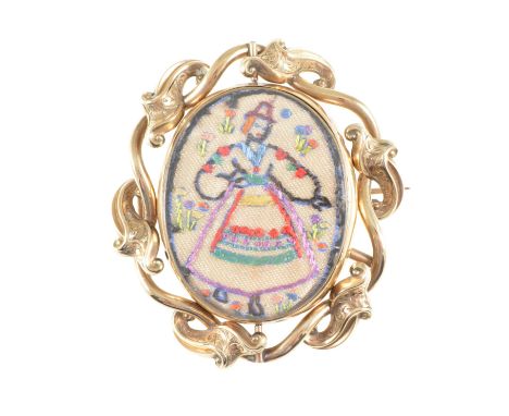A yellow metal brooch with scroll edge frame, needlework panel to front and photograph of an Edwardian lady to back, overall 