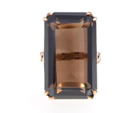 A 1970s smoky quartz dress ring, the rectangular step cut stone 25mm x 15mm, set with four double corner claws in a 9 carat y