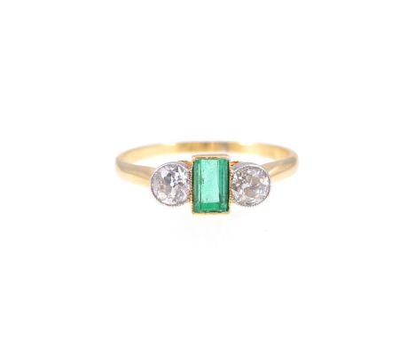 An emerald and diamond three stone ring, the rectangular step  cut emerald 4.5mm x 3mm having an old brilliant cut diamond to