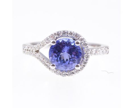 A tanzanite and diamond cluster ring, the brilliant cut 7.4mm tanzanite four claw set and encircled by a loop of thirty five 