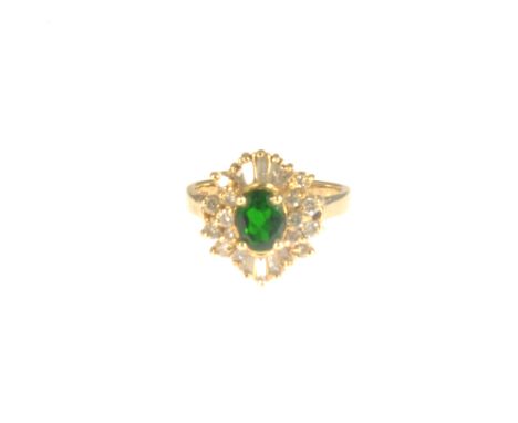 A chrome diopside and diamond cluster ring, the oval chrome diopside 6.5mm x 5mm, four claw set and having seven brilliant cu
