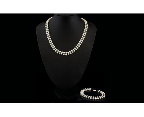 A Double Strand Cultured Pearl Necklace Together with matching bracelet, each with silver clasps, necklace length 18 inches. 