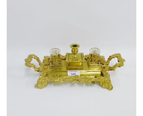 Brass desk ink stand with two glass inkwells and a candlestick to centre, 32cm long