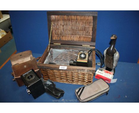 A lidded basket with a Polaroid land Camera, a Rex box camera in leather case and a duck clothes brush