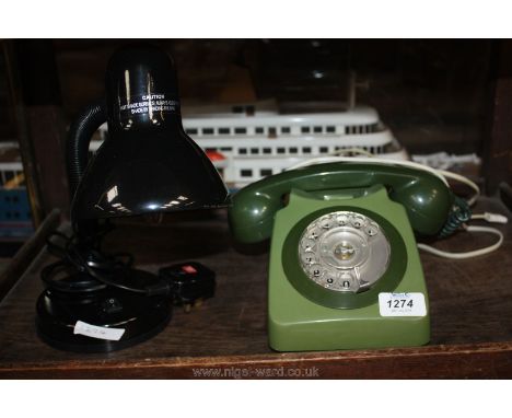 An old green Telephone and a modern black desk Lamp