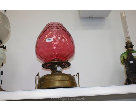 A brass Oil Lamp with cranberry glass shade, wick turner marked 'R.A.L. & Co. Ltd. Century'