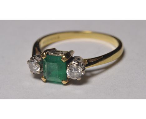 18ct gold engagement ring set with table cut emerald flanked by twin diamonds, stamped 750, hallmarked. Weight: 3.1g