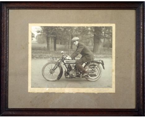 Circa 1920 black and white photograph of a man wearing cap riding a Zenith motorcyle, signed in pencil in the mount, in woode