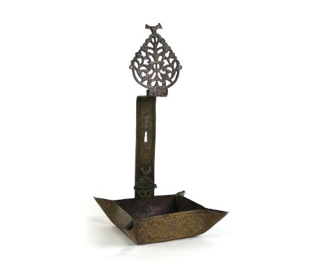 A Middle Eastern engraved brass wall mounted oil lamp, 34cms (13.5ins) high; together with a Hindu or Islamic wrought iron pe