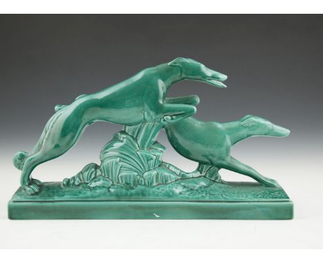 AFTER CHARLES LEMANCEAU, an Art Deco green glazed ceramic group of two running hounds, impressed signature. 54 x 12.5 x 31cm 