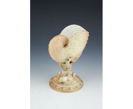 A ROYAL WORCESTER PORCELAIN BLUSH NAUTILUS SHELL VASE, supported in a coral branch on a circular base with sea shells and gil