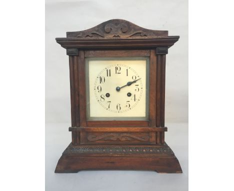 A wooden cased mantel clock with carved pediment, cream dial with Arabic number 39cmH