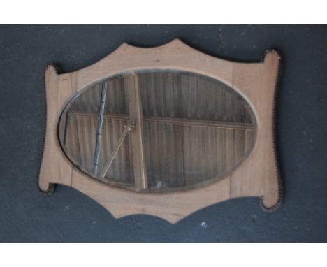 An Arts and Crafts oak mirror with bevelled oval glass together with a ceramic lamp 78cmW