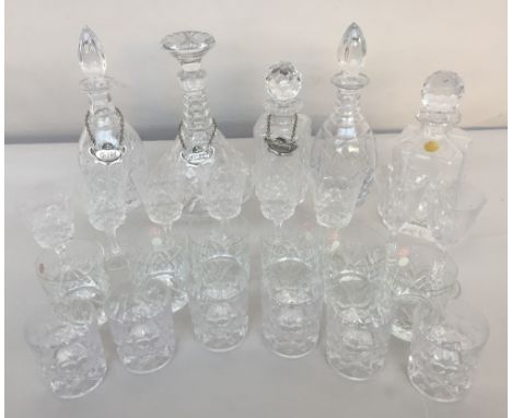 A selection of four decanters in cut crystal three with Gin, Whiskey, and Cognac labels with a small selection of wine glasse