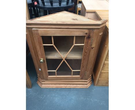 A pine corner display cabinet with carved pediment over astragal door, internal shelf and brass handle 67cm W