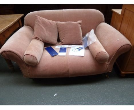 A Multi York two seater peach upholstered sofa raised on turned legs and castors, with removable covers and original labellin