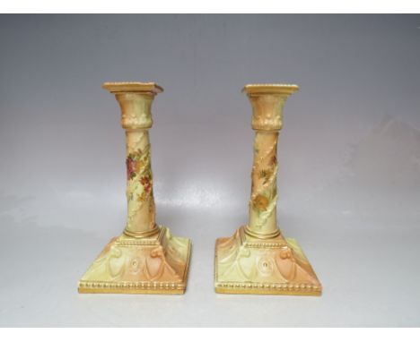 A PAIR OF ROYAL WORCESTER BLUSH IVORY CANDLESTICKS, decorated with hand painted floral and raised gilt detail, printed marks 
