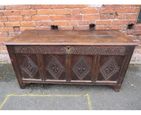 A LATER 18TH CENTURY CARVED OAK FOUR PANEL COFFER, the hinged lid opening to reveal a carved panel initialled 'I G', raised o