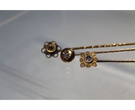 A DIAMOND SET YELLOW METAL STICK PIN, together with a yellow metal gem set example and a hallmarked silver gilt stick pin (3)