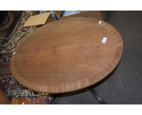 An oval coffee table with tripod legs and claw feet