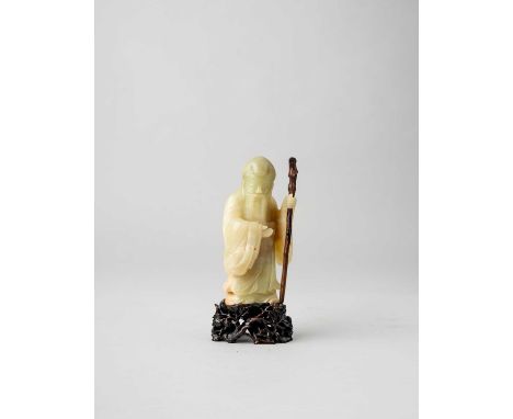 A CHINESE YELLOW JADE CARVING OF SHOULAO18TH CENTURYThe smiling deity wearing flowing robes supporting himself on a wooden st