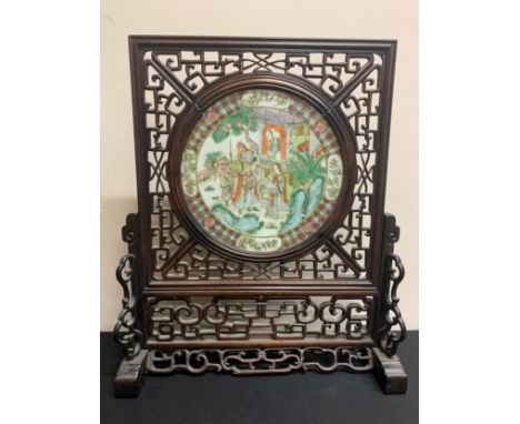 A Chinese hardwood screen with ceramic circular plaque to centre.56cm high, width at base 46.5cm, at top 40.5cm. Plaque 26cm 