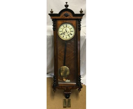 A walnut cased pendulum wall clock with enamel face and Roman numerals, brass weights and winding handle. Case approx. 122cms
