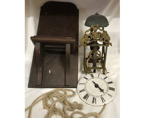 A 19thC brass framed lantern clock for restoration, enamel dial with an oak wall mounted bracket shelf. Clock approx 35 h x 1