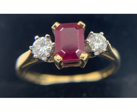 A three stone ruby and diamond ring the central ruby flanked by diamonds set in 18ct gold. Size Q. Total weight 3.9gms.Condit