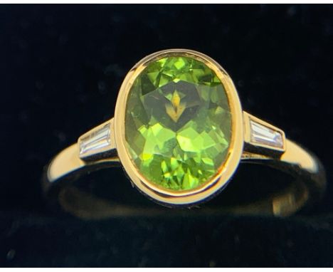 Peridot and diamond ring set in 18ct gold, central peridot flanked by baguette cut diamond. Size M/N. 3.9gms.Condition Report