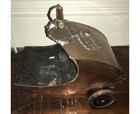 A Victorian copper coal helmet with wheels to the rear. 27 w x 42cms l.Screw missing to centre of one wheel.