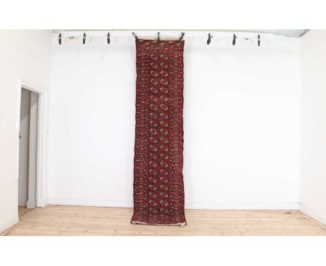 A Turkoman runner,20th century, the red fields with two columns of repeating guls and similar border,323cm x 74cmCondition Re