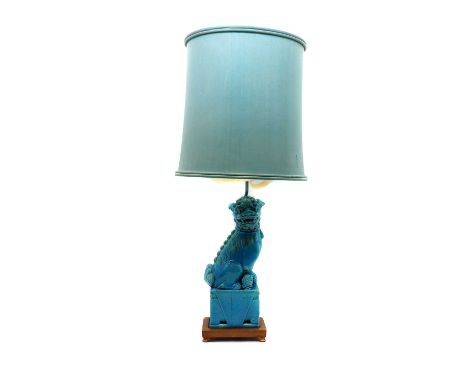 A Chinese dog of foo porcelain table lamp,20th century, in a blue glaze, on a wood stand, with an associated blue shade,the d