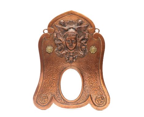 An Art Nouveau copper mirror,early 20th century, of ogee form, with a bevelled surface surmounted with a portrait relief of H