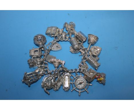 A SILVER CHARM BRACELET WITH NUMEROUS CHARMS TO INCLUDE COMPASS, SEDAN CHAIR ETC.