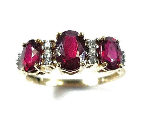A 14ct ruby and diamond ring, the central oval ruby measures 0.75ct approximately and flanked by two smaller rubies, punctuat