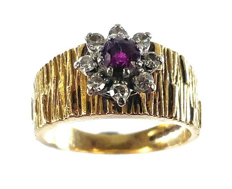 A 1960's 18ct gold diamond and ruby set cluster ring, the central ruby measures 0.25ct, the cluster on textured shank, size M