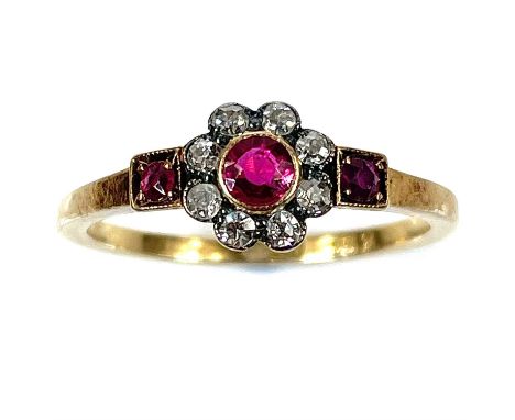 An early 20th century 18ct diamond and ruby set 12 stone daisy ring, the stones in milgrain setting, the central ruby measuri
